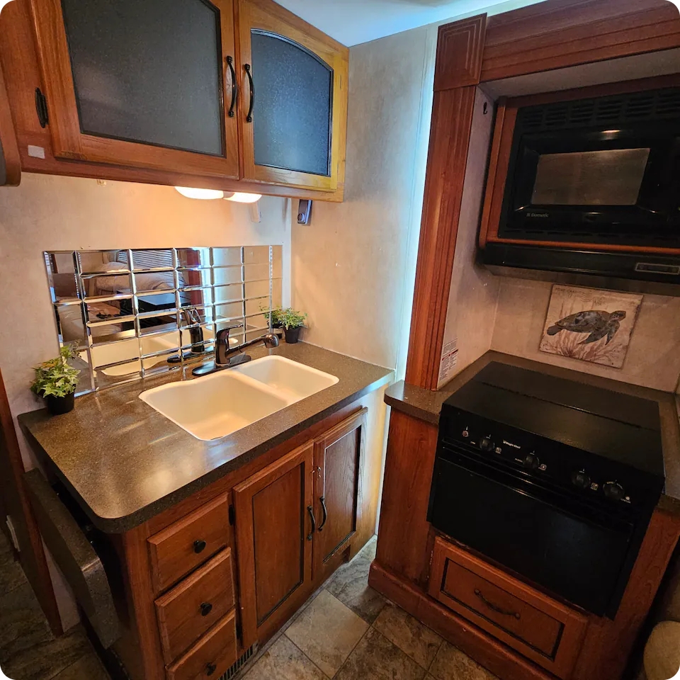 Coachman RV — compact kitchenette with sink, cabinets and stove