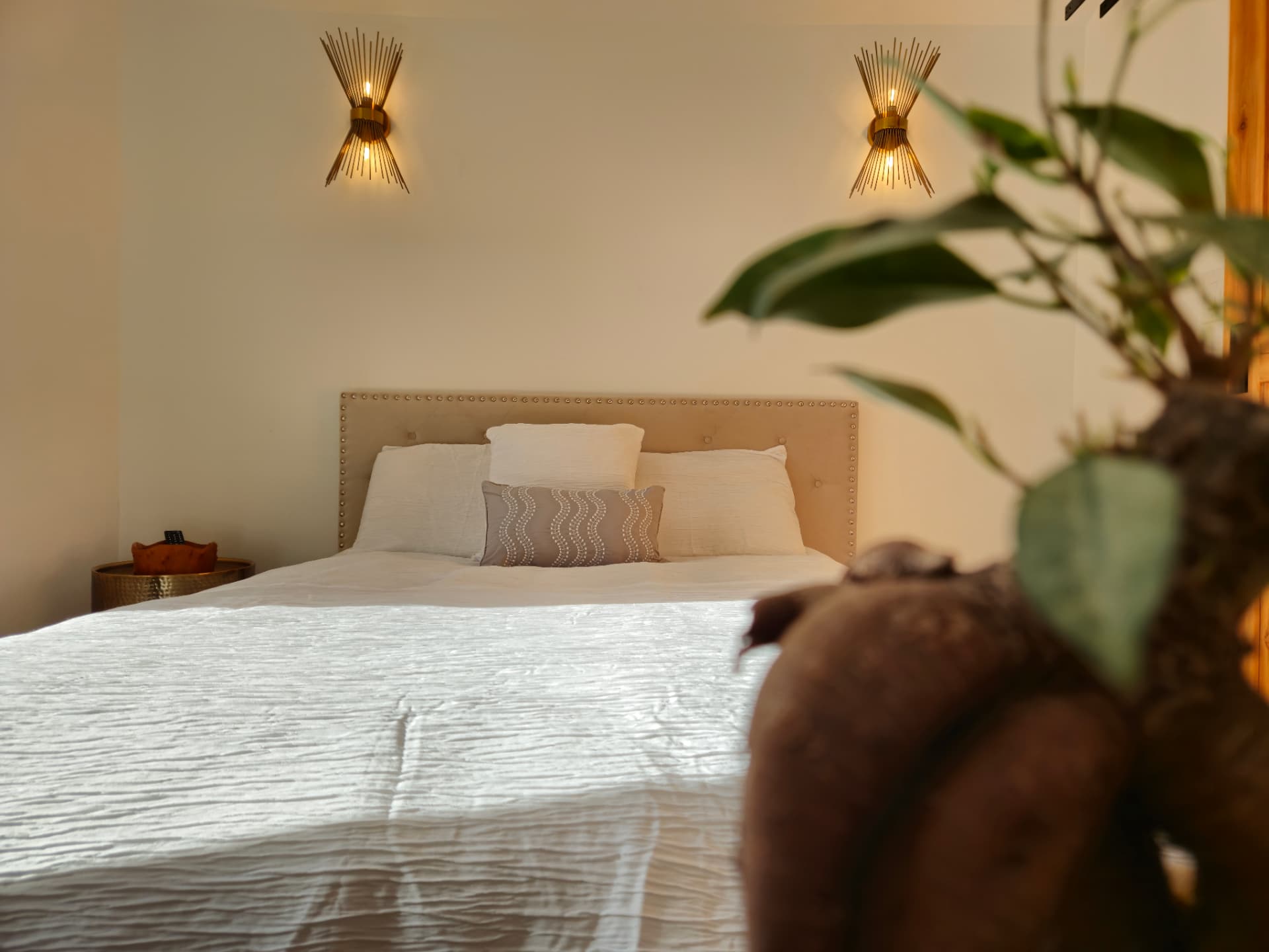 Urban Oasis — bed detail with brass sconces